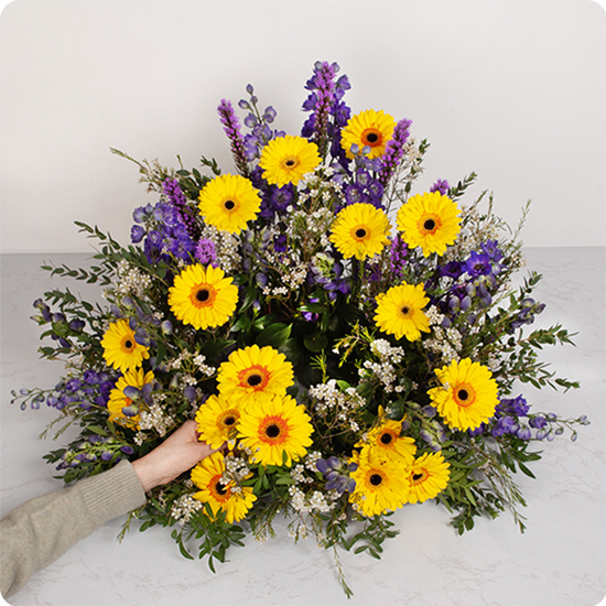 Cushion with gerberas and delphinium in yellow and purple tones